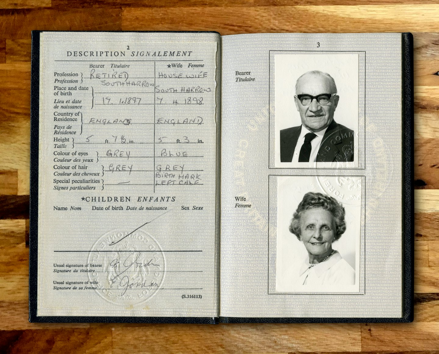 An open passport with portraits and stamps rests on wood.