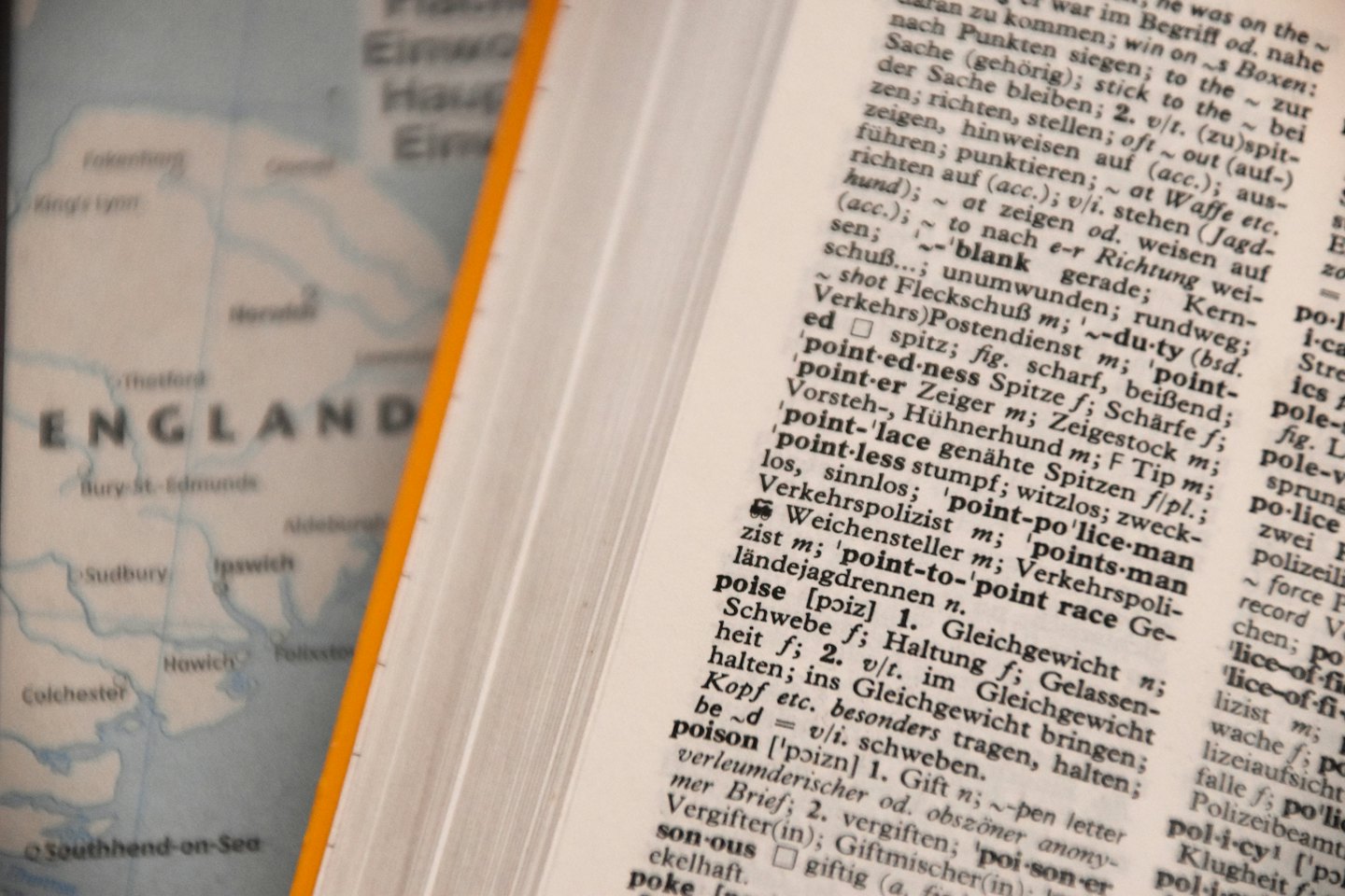 Open dictionary with English and German text on a map of England.